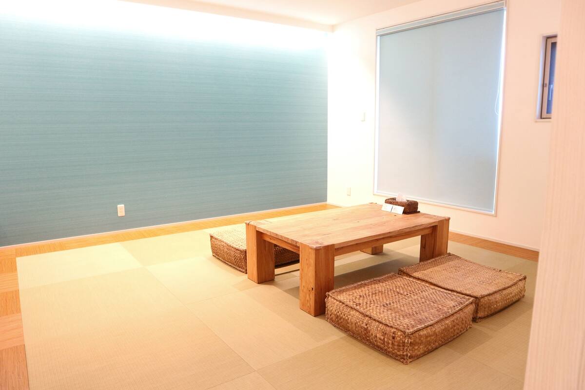 A room with tatami flooring, a wooden table, and woven mats.