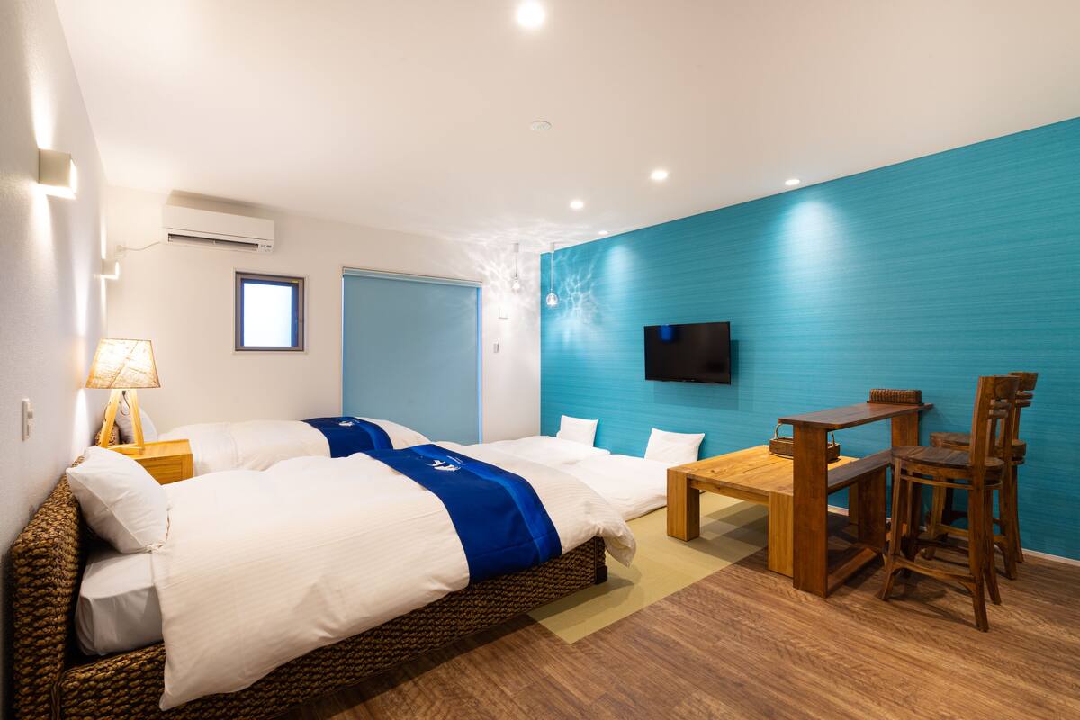 A hotel room with a bed, a desk, and a TV on the wall.