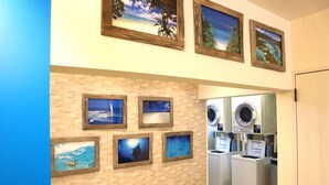 Un área de lavandería con varias lavadoras y secadoras, y varias fotografías enmarcadas en la pared.