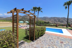 Un espace piscine agrémenté d’une pergola en bois, d’une piscine et offrant une vue sur les montagnes.