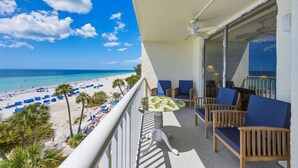 Ein Balkon mit Blick auf einen Strand, einem Deckenventilator und einem Tisch mit Stühlen.