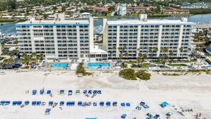 Ein Hotel mit mehreren Etagen, einem Poolbereich und einem Strand mit Liegestühlen.