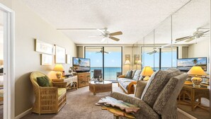 Ein geräumiges Wohnzimmer mit Balkon, Deckenventilatoren und Fernseher.