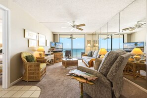 Un salon spacieux avec balcon, ventilateurs de plafond et télévision.