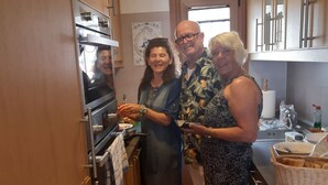 A narrow kitchen with wooden cabinets, a stainless steel oven, and a window. - Well-kept vacation home with pool and garden directly on the Cami de Cavalls. (Cala en Porter)