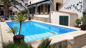A swimming pool surrounded by potted plants and a stone wall. - Well-kept vacation home with pool and garden directly on the Cami de Cavalls. (Cala en Porter)
