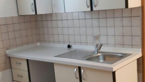 A compact kitchen with white cabinets, a sink, and a tiled backsplash. - Family holiday fun on the Croatian Mediterranean coast (Privlaka)
