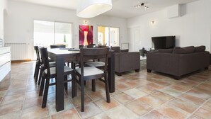 Un grand espace de vie comprenant une table à manger, des chaises, un canapé et un téléviseur.