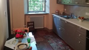 A kitchen with a window, a radiator, a sink, and a dining table with chairs.