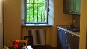 A kitchen with a window, a radiator, and a dining table with flowers.