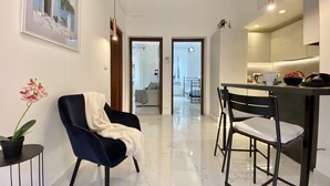 Una cocina moderna con comedor, una sala de estar con sofá, y un pasillo que conduce a un dormitorio.