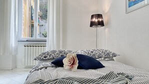 Un dormitorio con cama, ventana, radiador y lámpara.