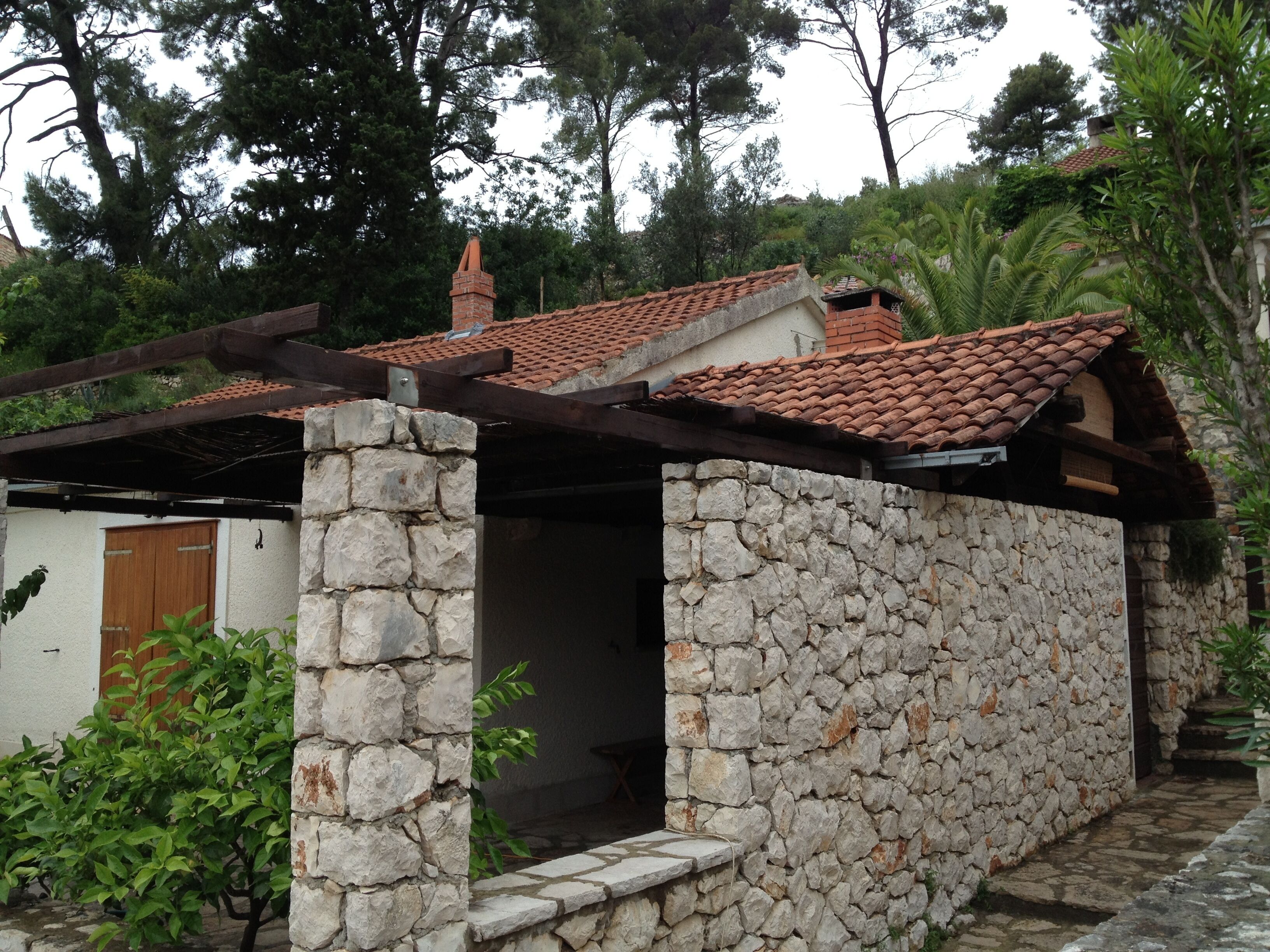 Un bâtiment en pierre avec un toit en tuiles, une porte en bois et un mur en pierre.