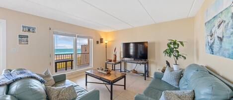 A living room with a sofa, coffee table, TV, and a balcony with a view.