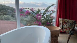 Un baño con bañera, una planta en maceta y una silla.