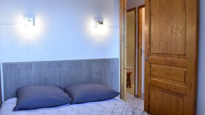 A bedroom with a bed, two wall-mounted lights, and a wooden wardrobe.