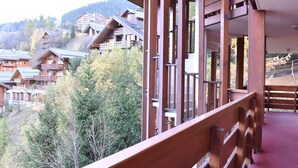 A wooden balcony with a view of traditional wooden buildings and trees in the background.