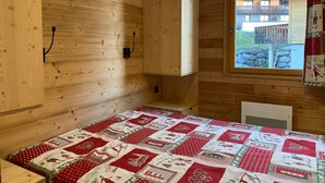 A wooden cabin room with a bed, a window, and a quilt. - 3-room apartment with balcony in Pra-Loup, private parking (Pra-Loup)