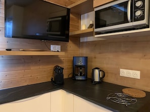 A kitchen with a microwave, coffee maker, and a kettle on the counter.