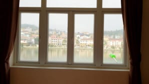 A window with a view of a cityscape across a body of water. - Diamond Hotel Sapa (Sa Pa)