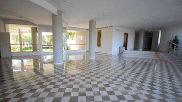 Un'ampia hall con pavimento a scacchi, colonne imponenti e vista sull'esterno.