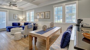 Un salon moderne avec un canapé bleu, une table basse en bois et un coin repas doté d’un comptoir de cuisine.