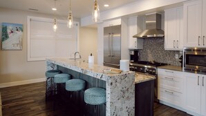 A modern kitchen with a marble island, stainless steel appliances, and bar stools. -   Luxury Ski-In/Out Town Lift Walk to Main St (Park City)