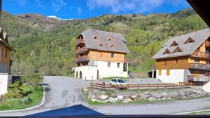 A mountain lodge with a wooden exterior, a balcony, and a view of the surrounding forest and mountains. - Beautiful duplex 65m², 6p, balcony, parking, WiFi (Pra-Loup)
