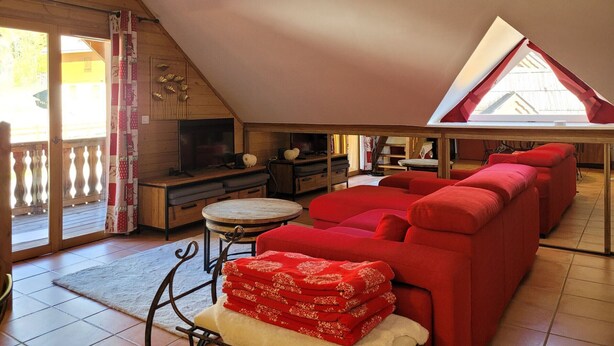 A cozy living room with a red sofa, a television, and a small table. - Beautiful duplex 65m², 6p, balcony, parking, WiFi (Pra-Loup)