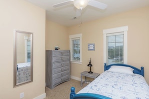 Quarto com cama, penteadeira e ventoinha no teto.