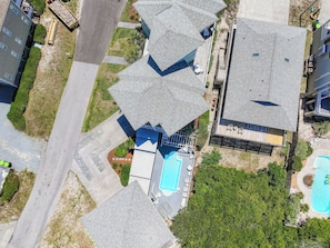 Vista aérea de um bairro residencial com várias casas, uma piscina e uma estrada.
