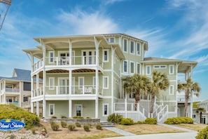A multi-story beachfront property with balconies, a covered porch, and a sign indicating 'Bland Shores'.