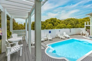 A pool area with a hot tub, lounge chairs, and a covered seating area.