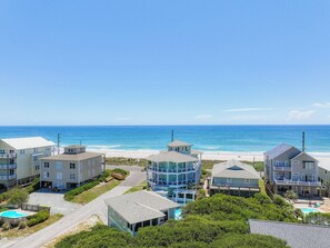 A beachfront property with multiple buildings, a swimming pool, and a clear view of the ocean.