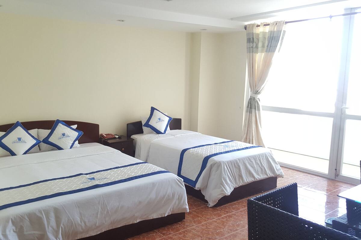 Habitación de hotel con dos camas, cada una con colcha y almohadas a rayas azules.
