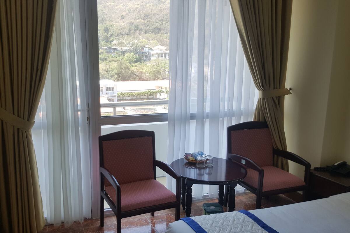 Una habitación de hotel con dos sillones, una mesita y una cama.