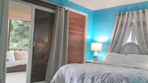 Un dormitorio con cama, cortinas, mesita de noche y lámpara.