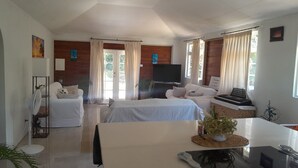 Habitación de hotel con dos camas, televisión, escritorio con computadora y una mesa de comedor.