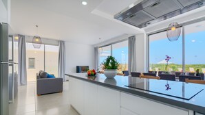 A modern kitchen with a large island, a dining area with chairs, and a view of the outdoors. - Coral Beach Villa 5 Bedroom 5 Bathroom 200m from Coast 700m from Coralia Beach (Peyia)
