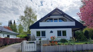A two-story house with a white exterior, a dark roof, and a small porch with a white railing. - Stylish apartment in a fantastic location right on Volkspark (FL)