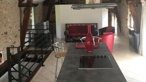 A kitchen with a central island, a staircase, and a living area with a sofa and red chairs. - Périgord - Country house (Beynat)