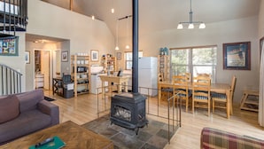 Amplia sala de estar con chimenea, mobiliario de madera y cocina equipada con electrodomésticos modernos.