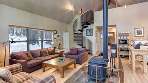 Una sala de estar acogedora con chimenea, una escalera y una zona de cocina con microondas.