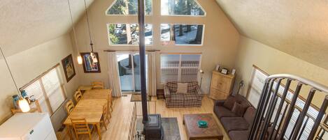 A spacious loft with a high ceiling, large windows, a fireplace, and a dining area.