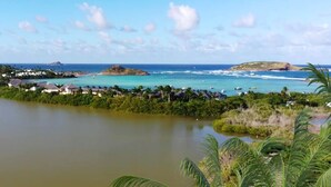 Vista costera con cielo despejado, agua tranquila y una pequeña isla con edificios.