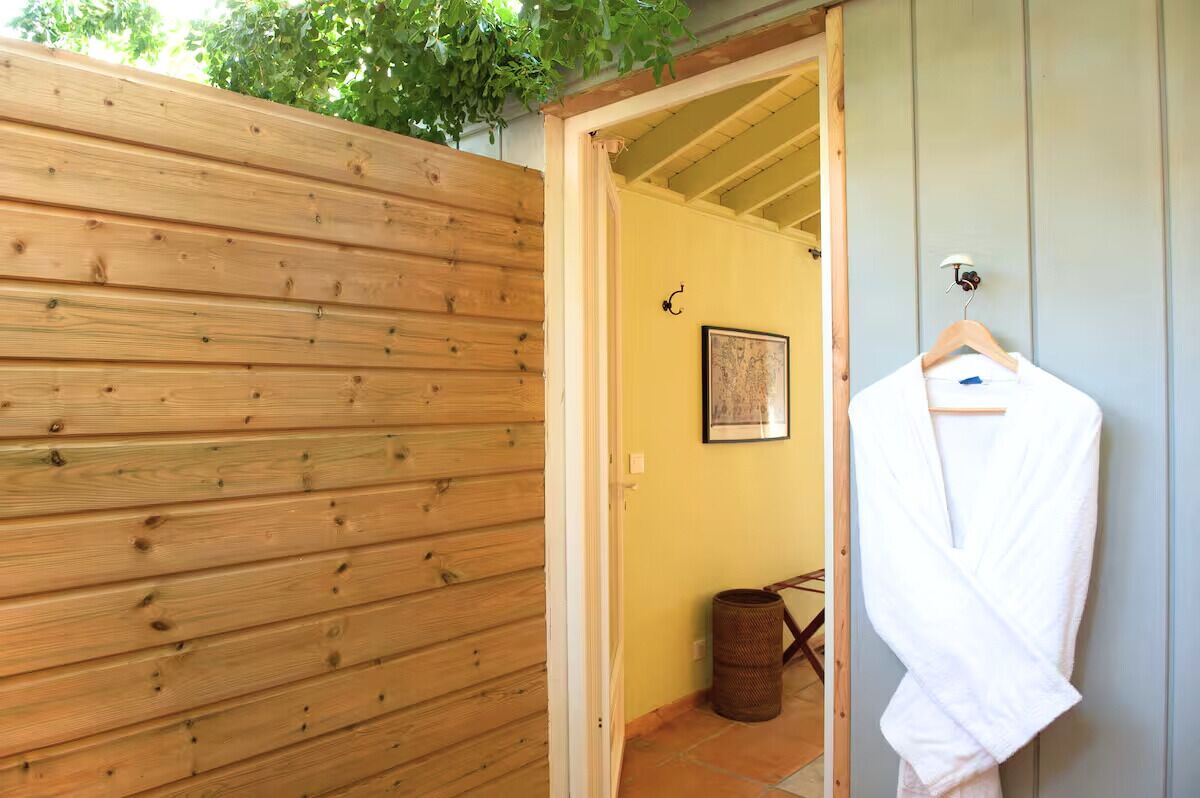 A wooden fence, a white robe on a hanger, a framed picture on the wall, and a trash can.