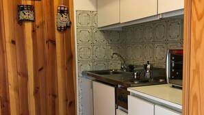 A kitchen with wooden walls, a clock, and a tiled backsplash.