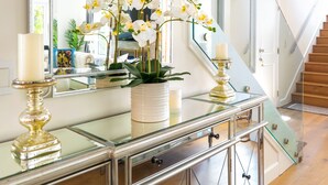 Een modern interieur met een glazen console tafel, een grote spiegel en een trap.