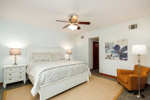 A bedroom with a bed, nightstands, a chair, a floor lamp, a ceiling fan, and a painting on the wall. - French Quarter Retreat 112 / Spacious Waterfront Home Near New Orleans (Slidell)