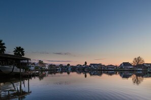 A waterfront residential area with houses and a dock with a boat. - French Quarter Retreat 112 / Spacious Waterfront Home Near New Orleans (Slidell)